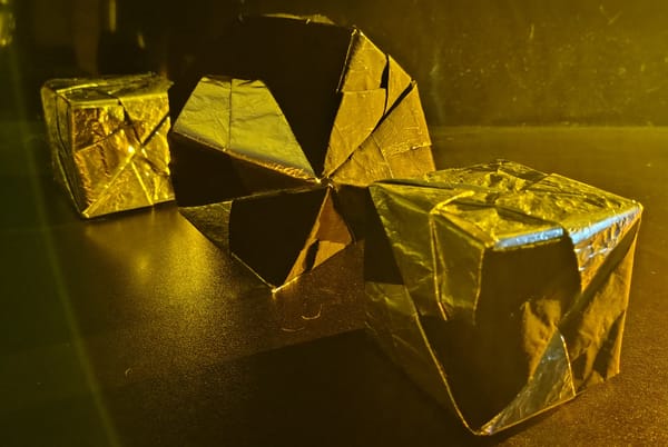 One silver cube in the background, an octahedron five-sixths pitch and one-sixth silver in the middle, and in the foreground a cube two-thirds silver and one-third pitch 